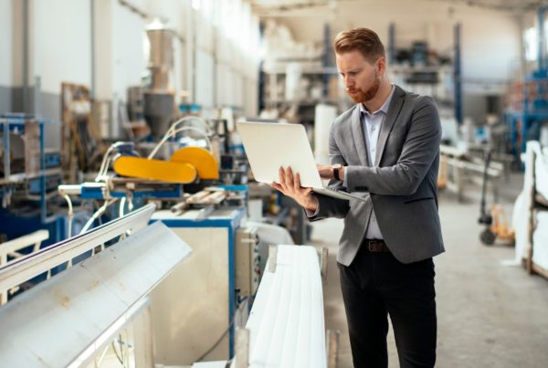 manager che utilizza un laptop in fabbrica per monitorare processi e fornitori nel settore manifatturiero tramite software oxalys